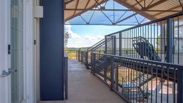 A covered outdoor area with a metal railing, a concrete floor, and a view of the landscape.