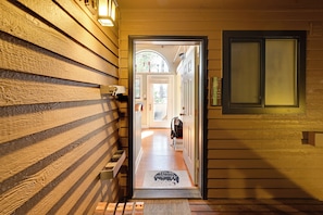 Corredor de madeira que leva a uma porta com tapete, porta-roupas e janela com vista para o exterior.
