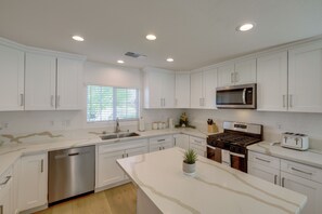A modern kitchen with white cabinetry, stainless steel appliances, and a marble countertop. - Coachella Getaway w/ Yard! Near Festivals & Golf (Coachella)