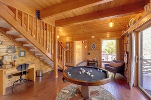 Un intérieur en bois avec une table de billard, un escalier et un canapé.