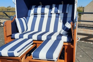 Una silla de lounge de madera con cojines a rayas azules y blancas.