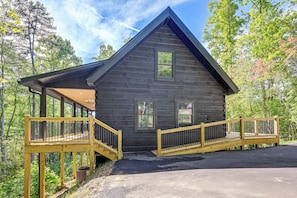 Eine Hütte mit überdachter Veranda, einer Treppe und einer Auffahrt.