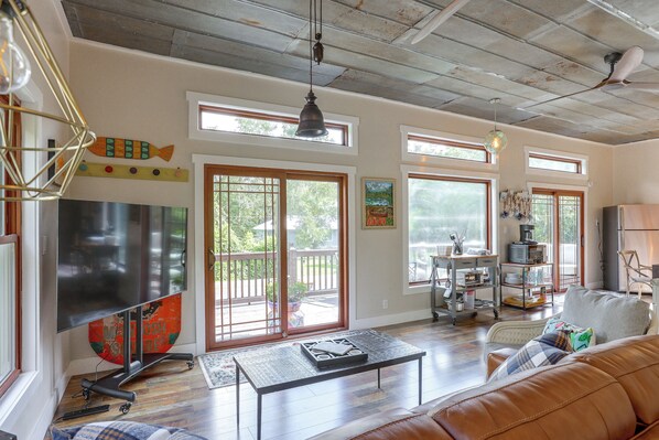 A spacious living room with a large flat-screen TV, a coffee table, and a leather sofa.
