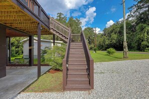 A wooden staircase leading to a covered porch with a view of a house and surrounding greenery. - Blue n Hall Fish House, Steps From the Marina! (Darien)