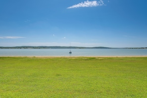 Ein grünes Feld mit einem ruhigen Gewässer und einer entfernten Küste.