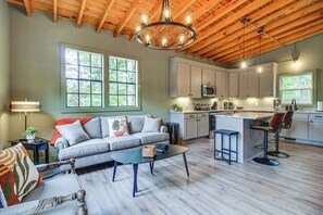 A spacious living area with a sofa, coffee table, and a kitchen with a bar area.