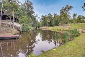 Een rustgevende oever met een houten steiger, een stenen gebouw en een gazon met bomen.