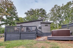 A wooden cabin with a fenced deck and a hot tub.