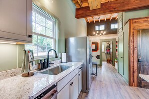 A kitchen with a stainless steel refrigerator, a double sink, and a wooden ceiling.