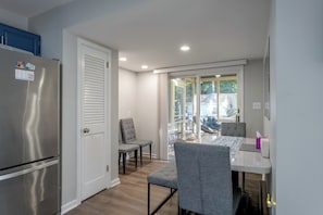 A compact kitchen with a refrigerator, a door with a window, and a dining area with a table and chairs. - Screened Porch & Steps to Lake! Pocono Summit Home (Pocono Summit)