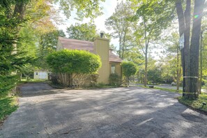 A residential driveway leading to a house with a covered porch, surrounded by trees and a clear sky. - Screened Porch & Steps to Lake! Pocono Summit Home (Pocono Summit)
