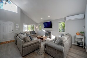 A modern living room with a sofa set, a coffee table, and a flat-screen TV mounted on the wall. - Screened Porch & Steps to Lake! Pocono Summit Home (Pocono Summit)