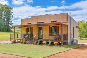 A two-story wooden building with a covered porch, outdoor seating, and potted plants. - Refined Rustic Retreat: Custom Designed by Owners (Washington)