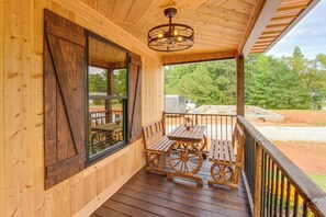 A wooden porch with a table and benches, a ceiling fan, and a view of the outdoors. - Refined Rustic Retreat: Custom Designed by Owners (Washington)