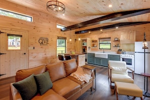 A cozy cabin interior with a wooden interior, a leather sofa, a dining area, and a kitchen with modern appliances. - Refined Rustic Retreat: Custom Designed by Owners (Washington)