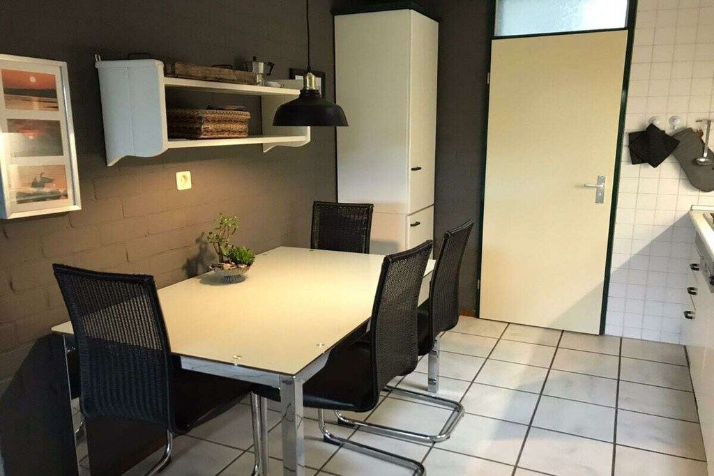 A compact kitchen with a dining table, chairs, a cabinet, and a tiled floor.