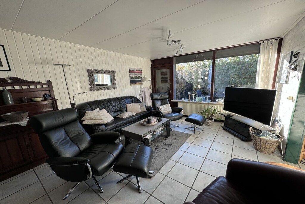 A living room with a sofa, a coffee table, a television, and a large window.