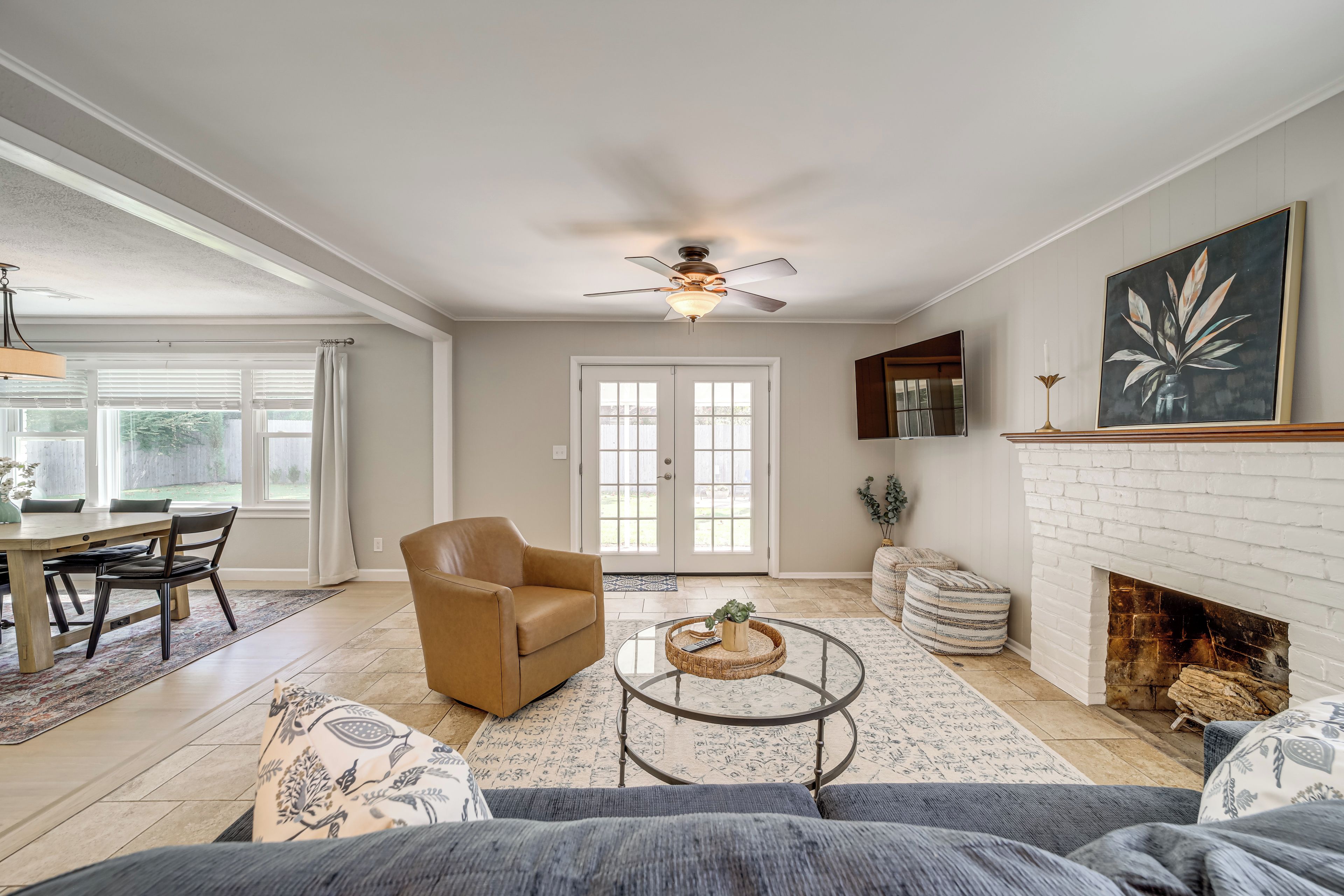 A spacious living room with a fireplace, a dining area, and a ceiling fan.