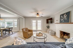 A spacious living room with a fireplace, a dining area, and a ceiling fan. - Charming Tulsa Home near LaFortune Park (Tulsa)