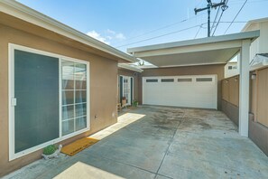 A residential garage with a white door, a covered driveway, and a small garden area with a doormat. - Walk to Beach & Dtwn! Extended San Clemente Escape (San Clemente)