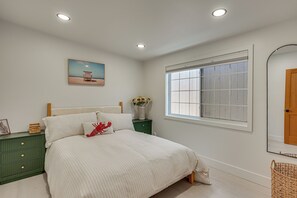 A bedroom with a bed, a nightstand, a window, and a painting on the wall. - Walk to Beach & Dtwn! Extended San Clemente Escape (San Clemente)