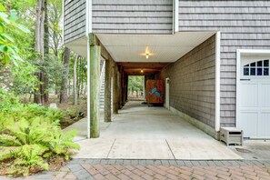 A covered walkway leading to a garage with a wooden door, surrounded by greenery. - Walk to Beach! 7BR Group Retreat in Bethany Beach (Bethany Beach)