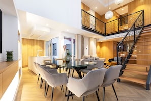 Ein modernes Interieur mit Essbereich, Küche und einer Treppe, die in einen oberen Bereich führt.