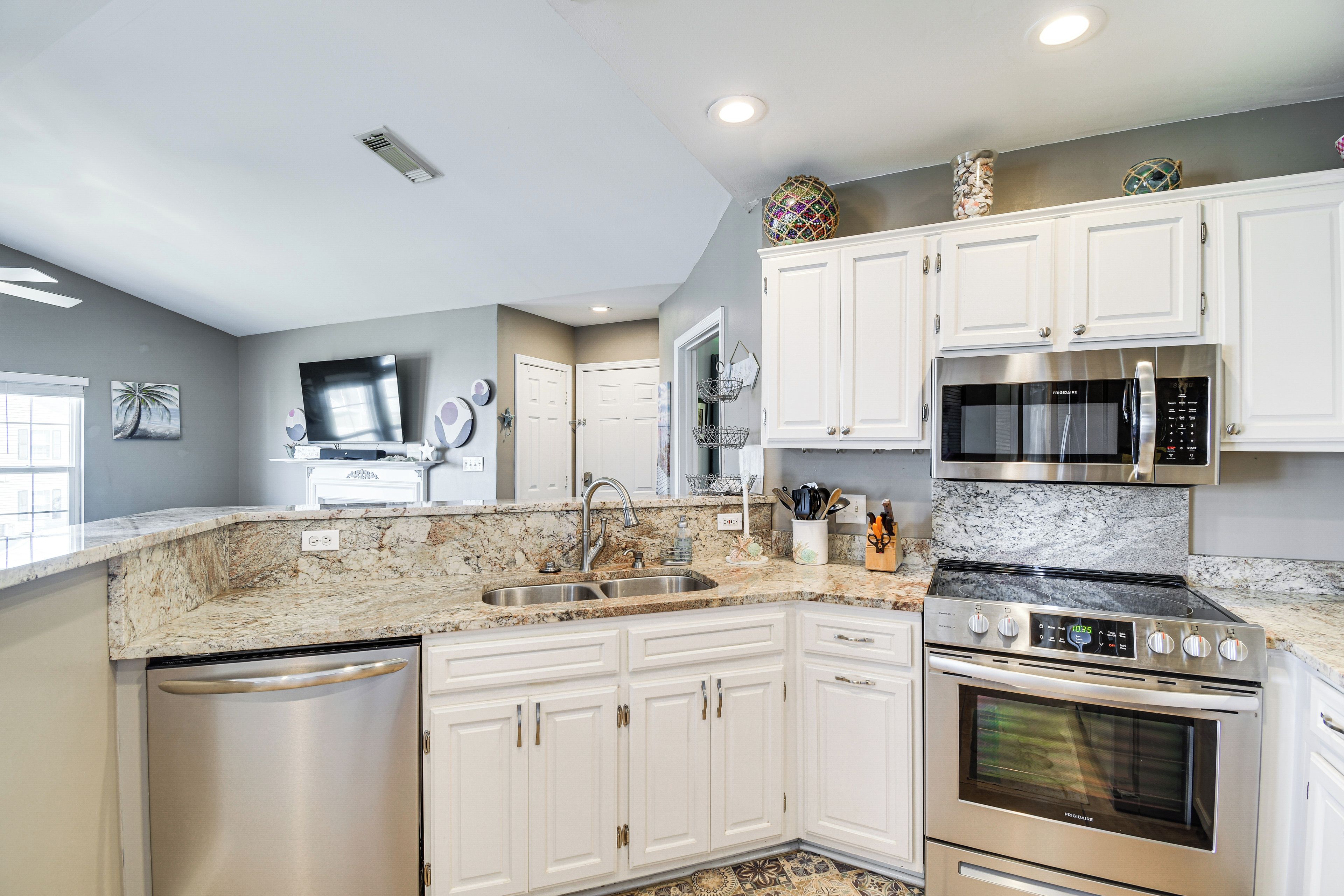 A modern kitchen with white cabinetry, a built-in oven, a microwave, and a stainless steel dishwasher.