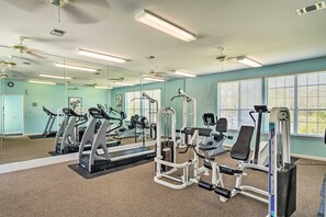 Ein Fitnessraum mit Trainingsgeräten, großen Spiegeln und Teppichboden.