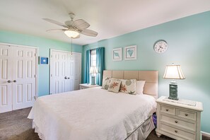 Ein Schlafzimmer mit Bett, Nachttischen, einer Uhr und einem Deckenventilator.