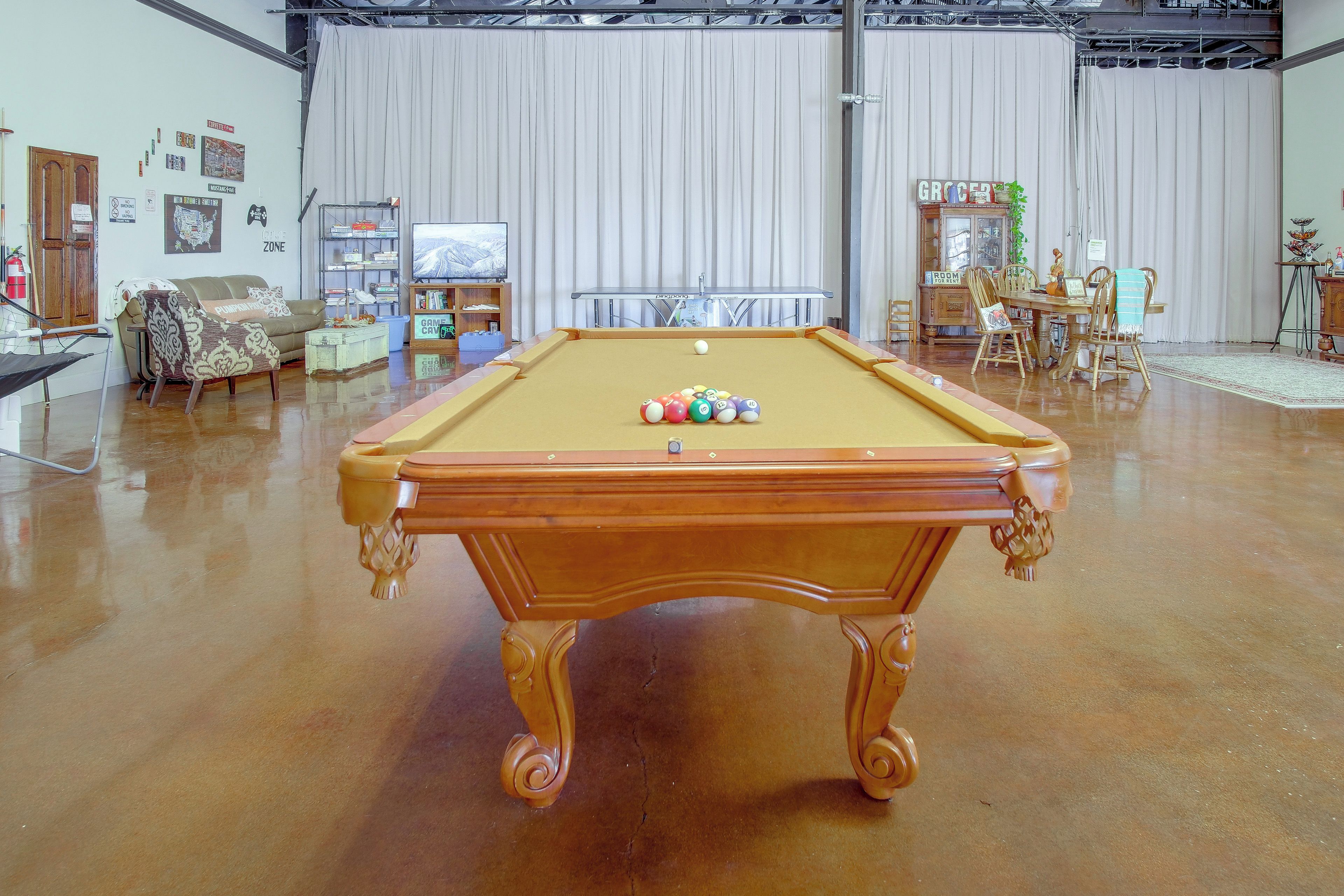 Une table de billard dans une pièce où se trouvent également une table à manger et différents types de chaises.