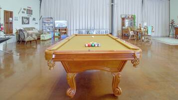 Une table de billard dans une pièce où se trouvent également une table à manger et différents types de chaises.