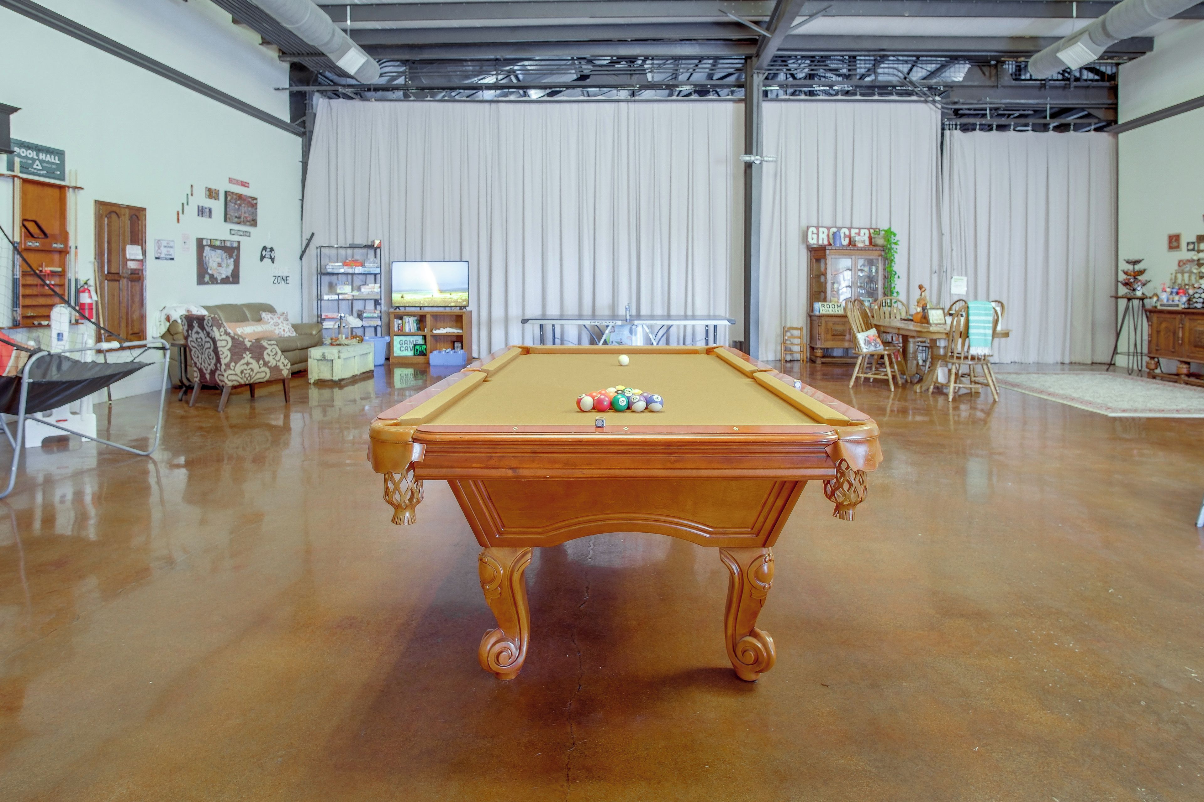 A spacious room with a pool table, a television, and a gaming area.