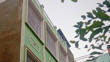 Un edificio de varios pisos con ventanas protegidas por barrotes y fachada verde.