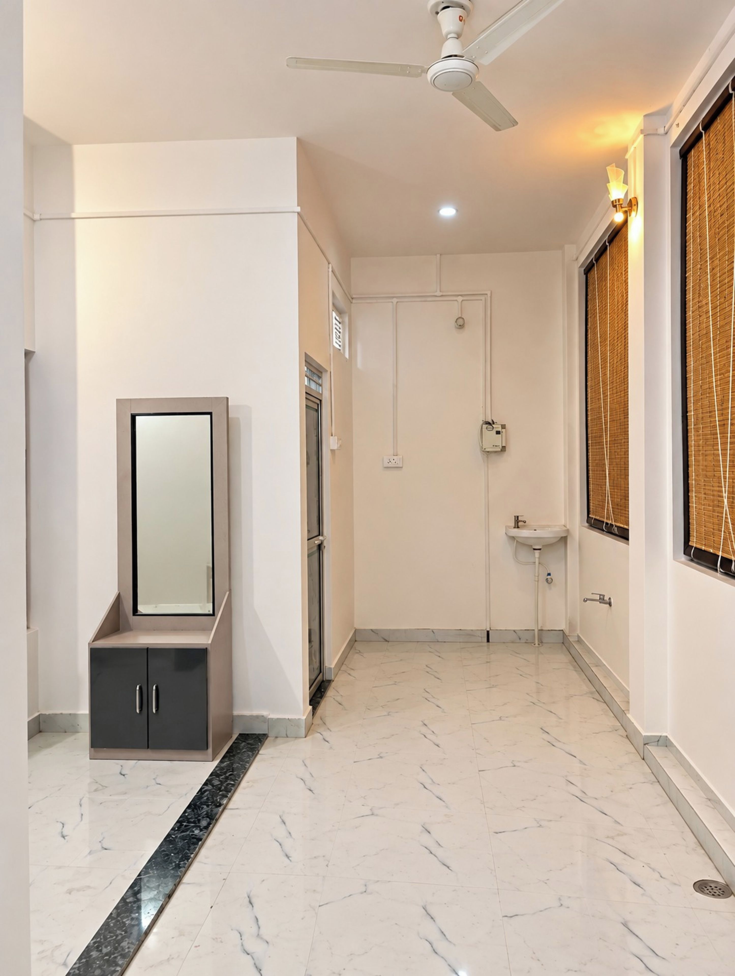Un baño moderno con tocador, espejo, lavamanos y ventilador de techo.
