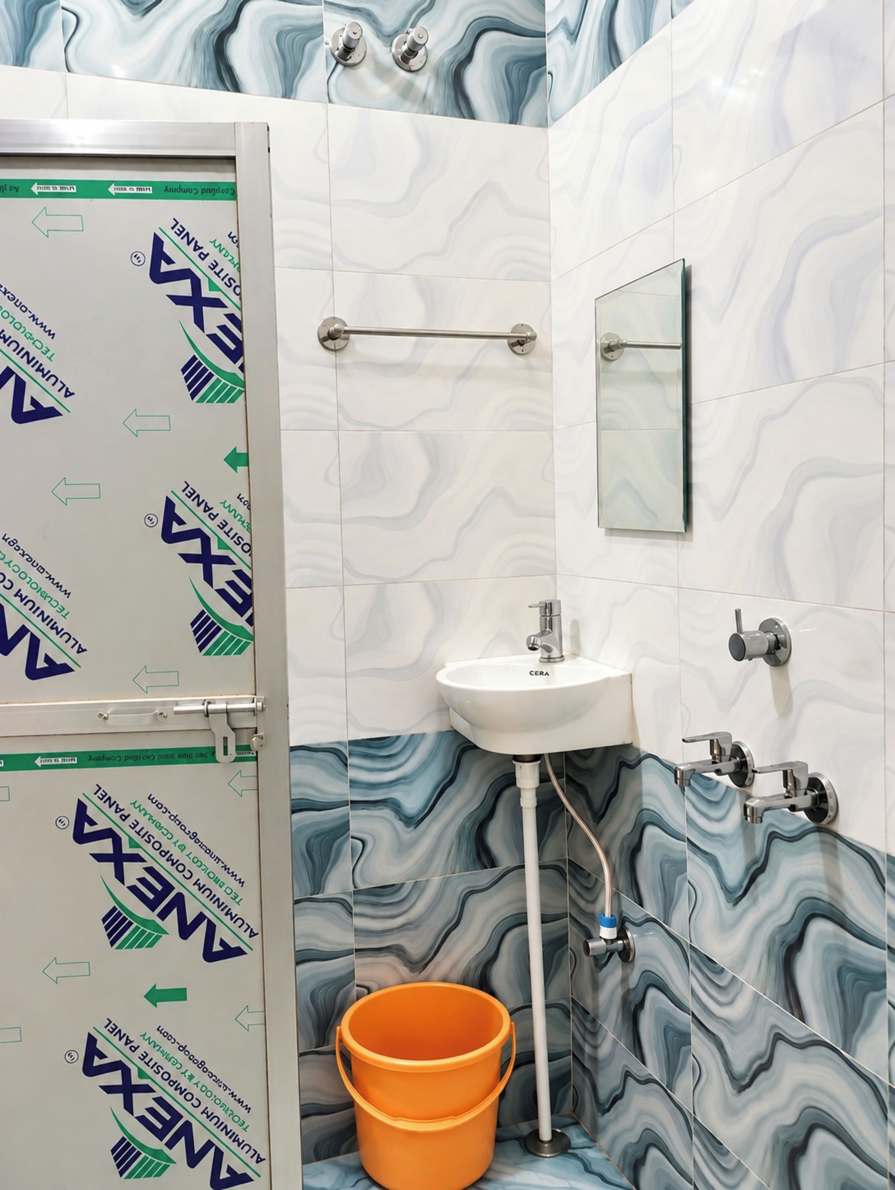 Un baño con un lavamanos blanco, un espejo y un perchero para toallas.