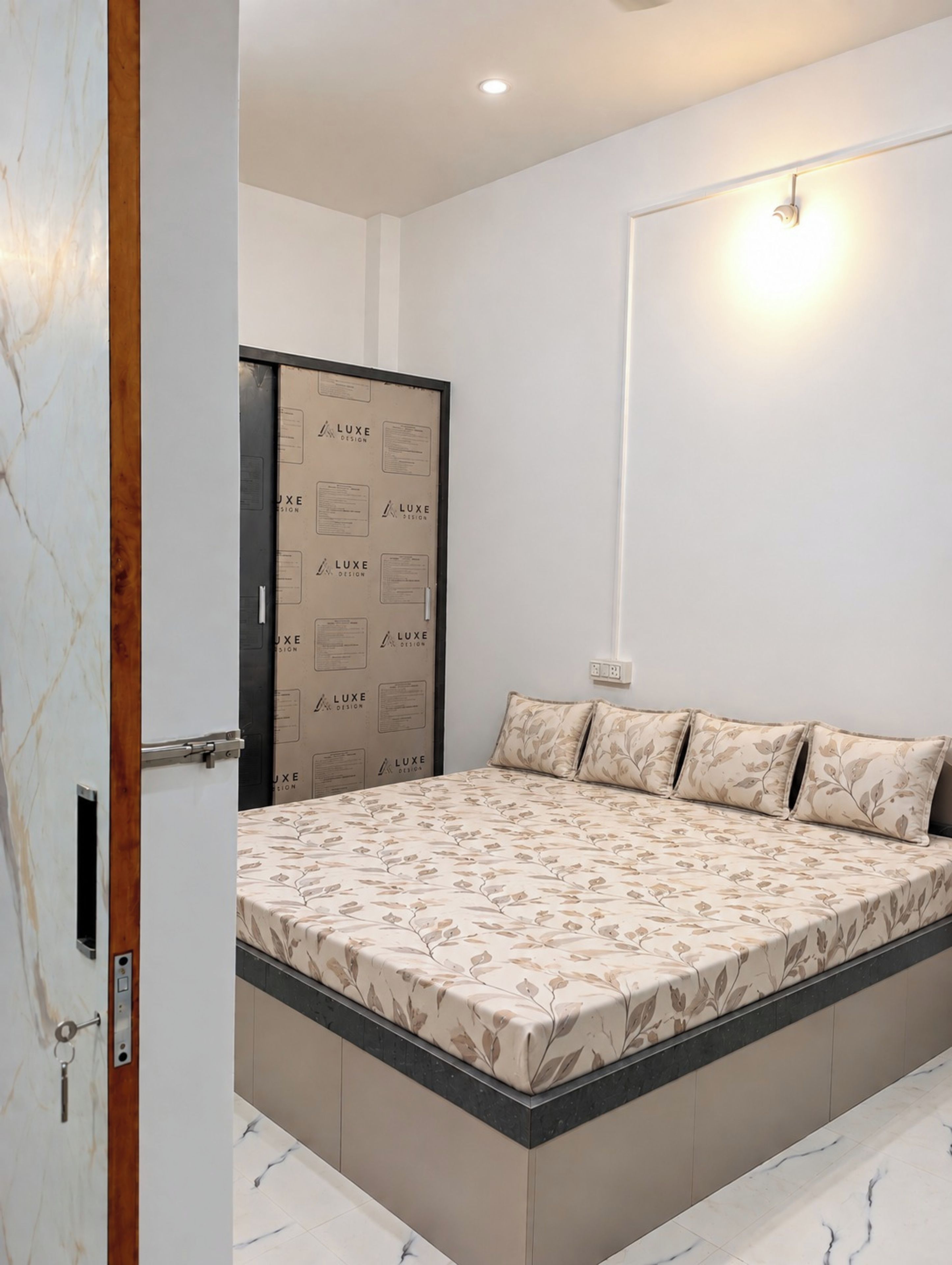 A bedroom with a bed, a wardrobe, and a wall-mounted light fixture.
