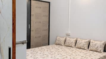 A bedroom with a bed, a wardrobe, and a wall-mounted light fixture.