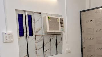 A room with a bed, an air conditioning unit, a wall-mounted cabinet with blue doors, and a wall with printed text.