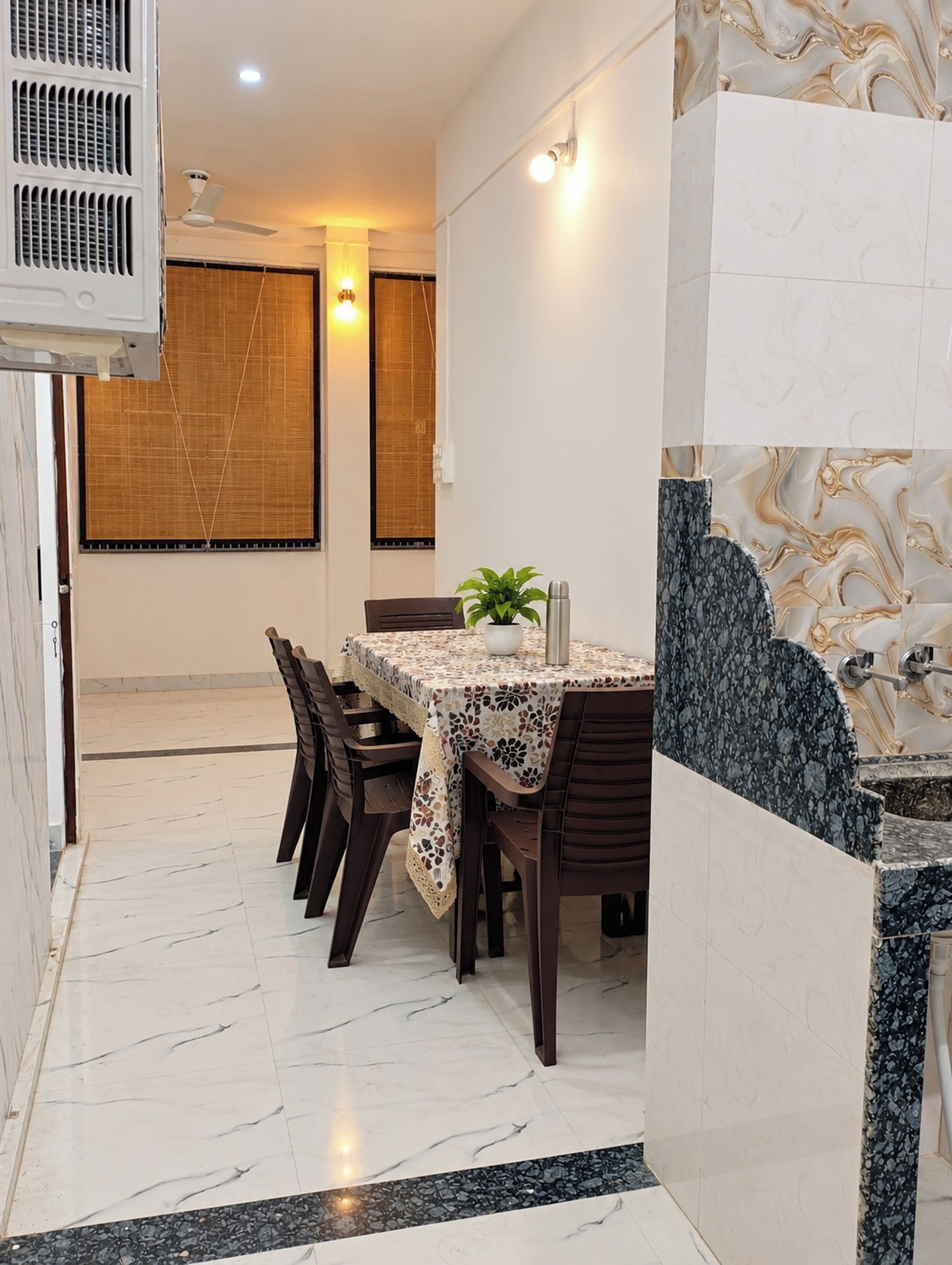 A dining area with a table set for four, surrounded by chairs, a ceiling fan, and a wall-mounted air conditioner.