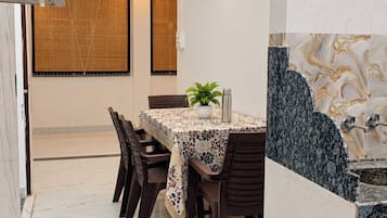 A dining area with a table set for four, surrounded by chairs, a ceiling fan, and a wall-mounted air conditioner.