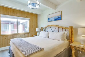 A bedroom with a wooden headboard, a large window, a painting on the wall, and a bedside table with a lamp. - Breckenridge Ski Condo: Easy Bus to Slopes (Breckenridge)