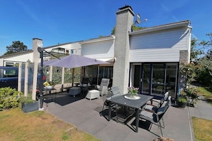 A modern house with a patio area featuring outdoor furniture and a table. - Ouddorp, Veermansplaat 47, Nordzeepark (Ouddorp)