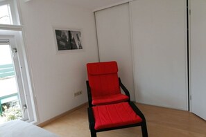 A room with a red chair, a white door, and a framed picture on the wall. - Ouddorp, Veermansplaat 47, Nordzeepark (Ouddorp)
