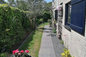 A pathway leading to a building with a brick exterior and dark shutters. - Ouddorp, Veermansplaat 47, Nordzeepark (Ouddorp)