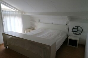 A bedroom with a bed, bedside tables, a window with curtains, and a wall-mounted light fixture. - Ouddorp, Veermansplaat 47, Nordzeepark (Ouddorp)