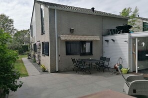 A two-story building with a patio area featuring a table and chairs. - Ouddorp, Veermansplaat 47, Nordzeepark (Ouddorp)
