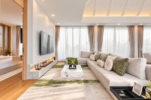 A modern living room with a sofa, a coffee table, and a flat-screen TV mounted on the wall. - Spacious 5-bedroom Private Pool Villa, 10 Min to Bang Tao Beach (Tambon Choeng Thale)