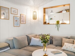 Ein modernes Wohnzimmer mit einer Eckcouch, einem runden Couchtisch und einem Spiegel darüber.