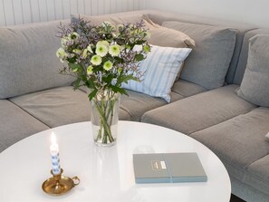 A round white table with a vase of flowers, a lit candle, and a book. - "Waghn" -  from the sea by Interhome (Hadsund)